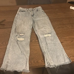Ljusa jeans med slitningar - Säljer ett par ljusa jeans med coola slitningar på knäna. De har en hög midja och en wide leg-stil som ger en avslappnad look. Perfekta för en casual outfit! 🕶️
