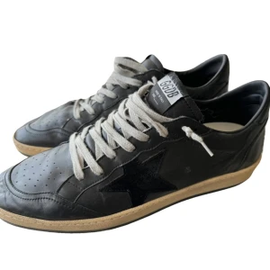 Svarta Golden Goose sneakers - Säljer ett par svarta GGDB Ballstar sneakers i skinn. De har en cool stjärndetalj på sidan och vit snörning. Sulan är i beige och grått med en stjärna på undersidan. Perfekta för en avslappnad och stilren look! Skick 7/10 OG: allt förutom kvittot!