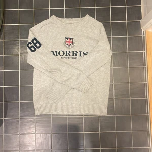Grå tröja från Morris - Säljer en snygg grå tröja från Morris med ett coolt tryck på bröstet och siffran 68 på ärmen. Perfekt för en casual look. Tröjan är knappt använd vilket betyder att den nästan ser helt ny ut. Säljer den på grund av att den inte kommer till användning!