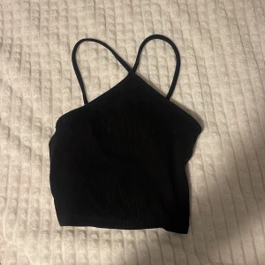 Svart ribbad linnetopp - Säljer en snygg svart ribbad linnetopp med smala axelband. Perfekt för sommardagar eller en utekväll. Toppen är i bra skick och passar till både jeans och kjol. Ett måste i garderoben för en stilren look!
