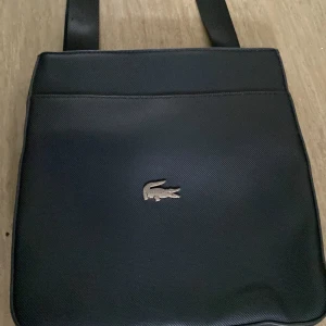 Lacoste väska - Mycket bra och knappt använd. Pris kan sänkas vid snabb affär