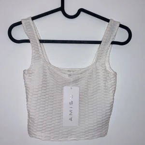 Vit ribbad linnetopp från Amisu - Snygg vit linnetopp från Amisu i ett ribbat material. Perfekt för sommardagar eller som ett basplagg i garderoben. Toppen är ärmlös och har en tight passform som framhäver figuren. Ny med tagg kvar!