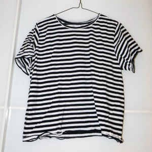 Svartvit randig t-shirt - Säljer en klassisk svartvit randig t-shirt i bomull. Den har en normal passform och korta ärmar, perfekt för vardagsbruk. T-shirten är i bra skick och passar både till jeans och shorts. Ett måste i garderoben för en stilren look!