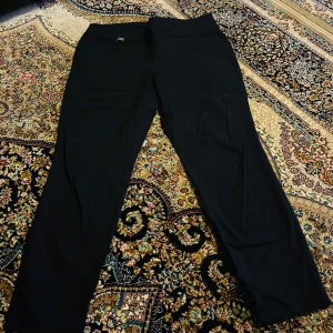 Svarta byxor från Alfani - Säljer ett par stilrena svarta byxor från Alfani i storlek 14S. De är perfekta för både vardag och fest med sin klassiska design. Byxorna har en rak passform och är tillverkade i ett bekvämt material. Perfekta för höst och vinter!