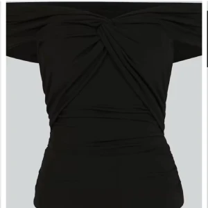 Svart offshoulder topp - Snygg svart offshoulder topp med en twistdetalj framtill. Perfekt för en utekväll eller fest. Den har en tight passform som framhäver figuren och är tillverkad i ett mjukt och stretchigt material.pris går att diskutera 