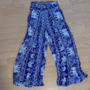 Mönstrade vida byxor i blått och vitt - Säljer ett par supercoola vida byxor med ett unikt mönster i blått och vitt. De är perfekta för sommaren med sitt lätta och luftiga material. Byxorna har en hög midja och ett elastiskt band för extra komfort. Perfekta för en avslappnad dag eller en sommarfest! 🌞