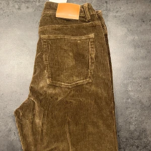 Bruna manchesterbyxor - Säljer ett par helt oanvända snygga bruna manchesterbyxor i mycket bra skick. De har en klassisk design och en bekväm passform. Perfekta för höst och vinter, och de ger en skön retrovibe. Passar både till vardags och lite mer uppklädda tillfällen. Aldrig använda med lappen kvar och de köptes för 500:- på CARLINGS från märket YOKE