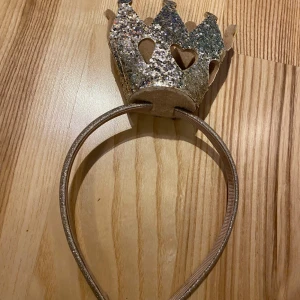 Glittrigt diadem med krona - Superfint diadem med en glittrig krona i guld. Perfekt för fester eller speciella tillfällen. Kronan har hjärtformade utskärningar och sitter på ett smalt, bekvämt band. Gör varje outfit lite mer magisk! ✨