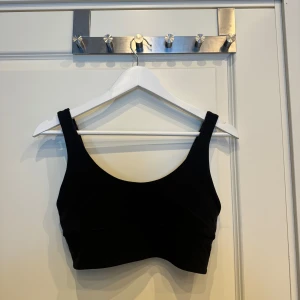Svart sporttopp från Lululemon - Säljer en svart sporttopp från Lululemon i mycket bra skick. Den är dubbelsidig och är i storlek 8 (M) och är helt oanvänd. Perfekt för gymmet eller yoga!