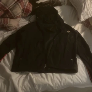 Moncler windbreaker  - Säljer en snygg svart jacka från Moncler. Den har en dragkedja framtill och är långärmad. Perfekt för höst och vår med sin stilrena design. Jackan har en broderad Moncler-logga på bröstet. Passar både till vardags och lite finare tillfällen.