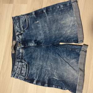 Säljer ett par snygga blå jeansshorts i bra skick. De har en klassisk femficksdesign och är perfekt för sommaren. Shortsen har en avslappnad passform och är gjorda av slitstarkt denim. Perfekta för en avslappnad stil eller en dag på stranden!