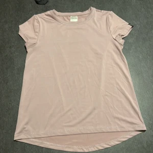 Ljusrosa/lila t-shirt - Säljer en ljusrosa/lila tränings t-shirt  . Den har en enkel och stilren design med korta ärmar och rund hals. Perfekt för träning och vardag. Är i mycket bra skick.