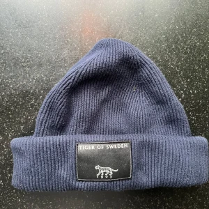 Tiger of Sweden mössa - Hej!  Säljer en tiger of sweden mössa, fint skick sparsamt använd!  Färgen är mörk blå.  Kostade 1200kr ny.  //Ludvig