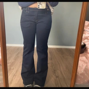 Lågmidjade Mörkblå jeans Mango - Mycket fint skick! Remmen i midjan knäpps med 2 synliga knappar samt finns det en knapp ovanför dragkedjan. De är stretchiga tyg och fickororna på baksidan är fake.   Första bilden är lånad😇 Skriv för frågor 🫶