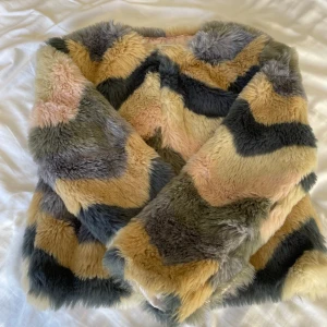 Flerfärgad pälsjacka från Name It - Säljer en supercool flerfärgad pälsjacka från Name It i storlek 146. Jackan har ett mönster i beige, grått och rosa med långa ärmar och knappar framtill. Perfekt för att hålla sig varm och snygg under hösten och vintern!