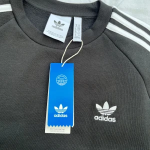 Adidas oversized crew svart - NYTT plagg, aldrig använd. Loose Fit. Modellen på (fjärde) bilden är 186 cm lång. Butikpris: 699kr