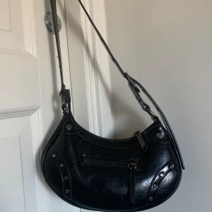 Svart axelremsväska  - Säljer en svart axelremsväska från even&odd med snygga detaljer då den inte används längre 😊 den är köpt på Zalando för 2 år sen, tyvärr verkar den inte finnas kvar men nypris är runt 200-250 kr! Priset är diskuterbart vid snabb affär 