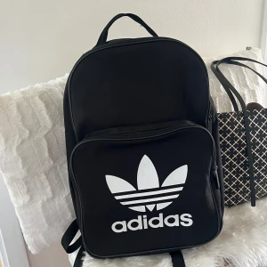 Adidas ryggsäck - Adidas ryggsäck vilken passar perfekt till jobb/skola. Väskan köptes för cirka fyra år sedan i en adidas butik och har varit sparsamt använd. Den rymmer en dator i det inre facket. Väskan är svart och har ett stort inne fack samt att mindre ytterfack
