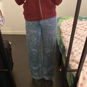 Blå mönstrade jeans från Stay - Säljer ett par snygga blå jeans från Stay med ett unikt blommönster. De är högmidjade och har en loose passform som ger en avslappnad stil. Perfekta för både vardag och fest! 🦋använt bara ett fåtal gånger, väldigt sköna och fina💕storlek xs men funkar som s. Köparen står för frakt om du inte hämtar i eksilstuna. Pris kan diskuteras!