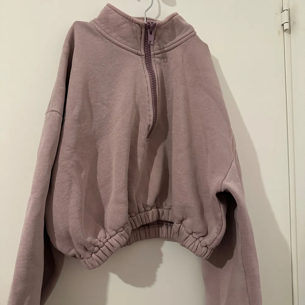 Mysig ljuslila hoodie i fleece med halv dragkedja framtill. Den har en avslappnad passform med elastisk nederkant och långa ärmar. Perfekt för kyliga dagar när du vill vara både bekväm och stilren.. Tröjor & Koftor.