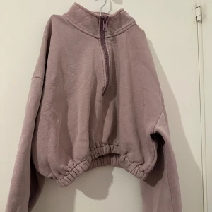 Ljuslila fleece hoodie - Mysig ljuslila hoodie i fleece med halv dragkedja framtill. Den har en avslappnad passform med elastisk nederkant och långa ärmar. Perfekt för kyliga dagar när du vill vara både bekväm och stilren.