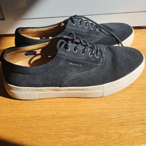 Svarta sneakers från Gant - Säljer ett par snygga svarta sneakers från Gant i storlek 44. De är gjorda i mocka och gjorda i Portugal. Skorna är i fint skick och bara använda ett fptal gånger