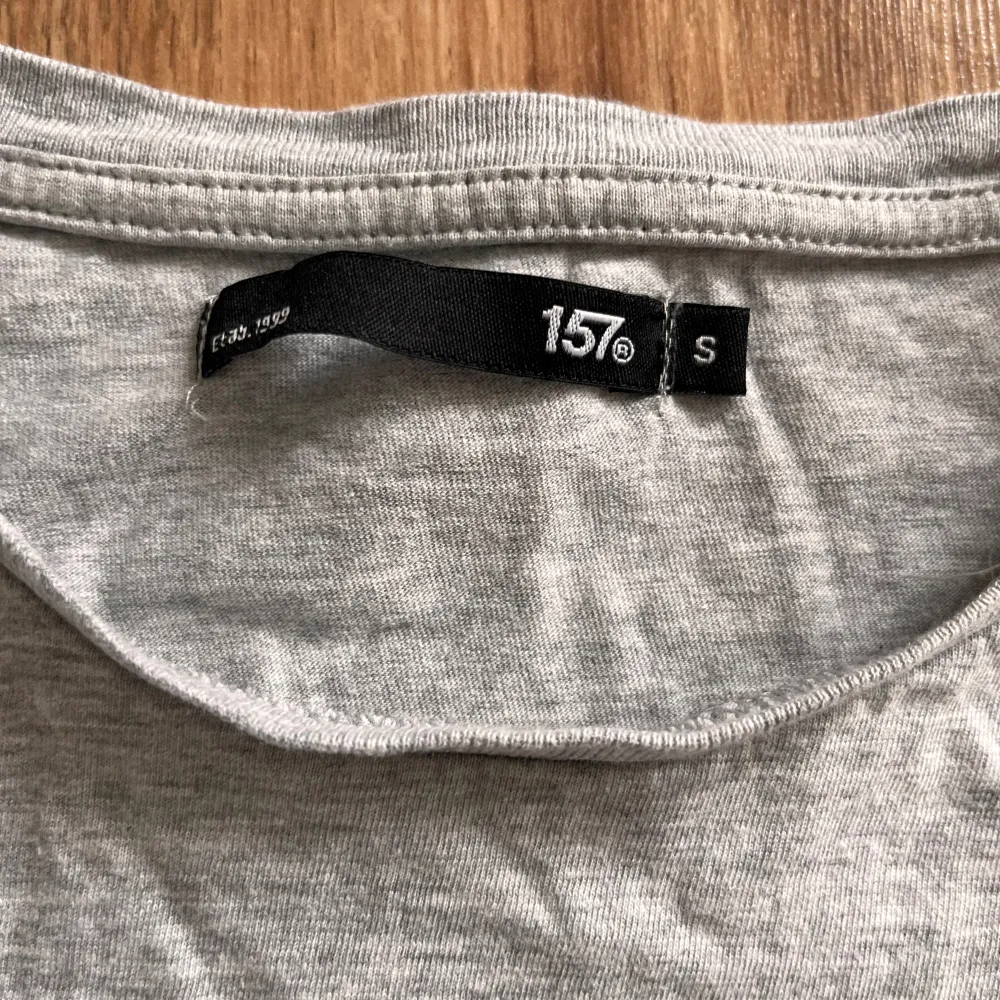 Säljer en grå t-shirt från Lager 157 i storlek S. Den är gjord av 95% bomull och 5% viskos, vilket gör den supermjuk och skön att ha på sig. T-shirten har ett tryck på framsidan med en byggnad och texten '157'. Perfekt för en avslappnad stil!. T-shirts.