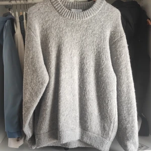 Grå stickad tröja från Vailent - Säljer en supermysig grå stickad tröja från Vailent i storlek S. Perfekt för kyliga dagar med sin mjuka och varma känsla. Tröjan har en klassisk rund hals och långa ärmar, vilket gör den idealisk för både höst och vinter. Den är i nyskick och redo att bli en del av din garderob! Köpt för ca 900kr på Brothers.