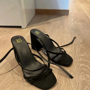 Svarta klackskor från XIT - Snygga svarta klackskor från XIT med en stilren design. De har en fyrkantig tå och smala remmar som ger en elegant look. Perfekta för festliga tillfällen eller en utekväll. Klacken är stabil och ger bra stöd. Skorna är i mycket bra skick och redo att användas! Använd endast 1 gång.