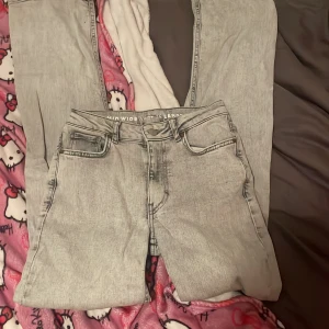 Grå jeans med wide fit - Säljer ett par grå jeans i mycket bra skick förutom ett litet hål på framsidan av ena låret skriv för bild på de. De har en wide fit och är midwaist, vilket gör dem både bekväma och trendiga. Perfekta för både vardag och fest! 🖤