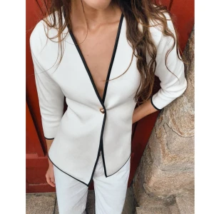 Vit omlottjacka från Zara - Säljer en stilren vit omlottjacka från Zara med svarta kanter och en enkel knappdetalj. Jackan har trekvartsärmar och en elegant v-ringad design. Perfekt för både vardag och fest!