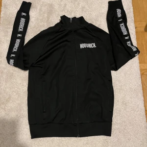 Hoodrich hoodie - Säljer en svart hoodie från Hoodrich i storlek M. Den har en dragkedja framtill och långa ärmar med Hoodrich-loggan tryckt längs ärmarna. Perfekt för en casual look eller träning. Hoodien är i mycket bra skick och redo för nya äventyr!
