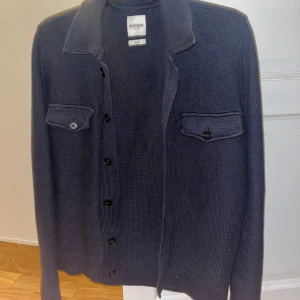 Mörkblå kofta från Dobber - Säljer en snygg mörkblå kofta/jacka från Dobber i mycket bra skick. Den har långa ärmar och knappar framtill samt två bröstfickor med knappar. Perfekt för höst och vår, både stilren och bekväm. Passar till både vardag och lite finare tillfällen.