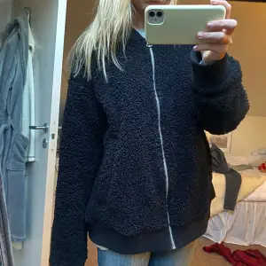 Mysig svart teddyjacka i oversized stil med dragkedja framtill. Perfekt för höst och vinter!