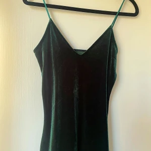 Grön sammetsklänning från Bik Bok - Säljer en elegant grön sammetsklänning från Bik Bok i storlek XS. Klänningen har en v-ringad design med smala axelband och är perfekt för festliga tillfällen. Materialet är mjukt och lyxigt, vilket ger en fin passform och känsla. Passar perfekt till höst- och vinterfester! 💚