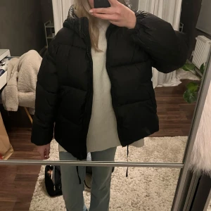 Svart pufferjacka - Säljer en svart pufferjacka i mycket bra skick. Den är perfekt för kalla dagar och har en skön, vadderad design. Jackan har långa ärmar och en dragkedja framtill. Den är både stilren och praktisk, idealisk för höst och vinter.