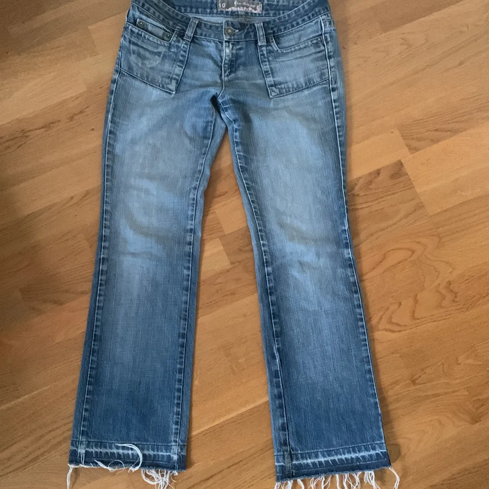 Säljer ett par snygga blå jeans i bra skick. De har en bootcut-stil och coola fransar vid bensluten. Perfekta för en avslappnad look! 🕶️. Jeans & Byxor.