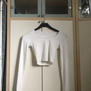 Vit croppad topp med mönster - Säljer en superfin vit croppad topp med ett unikt geometriskt mönster. Toppen har långa ärmar och är perfekt för både vardag och fest. Materialet känns mjukt och stretchigt, vilket gör den bekväm att bära. Passar perfekt till ett par höga jeans eller kjol!Hör av er om ni undrar något på 0764018475