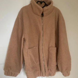 Ljusbrun teddyjacka - Mysig beige teddyjacka i mycket bra skick. Perfekt för höst och vinter med dragkedja och stora fickor. Jackan har en loose passform och är långärmad, vilket gör den superbekväm och varm. Ett måste för kalla dagar! 🧥✨