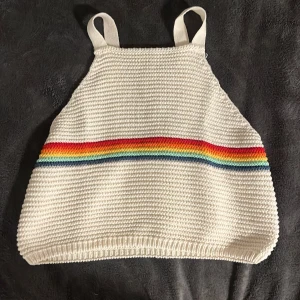 Vit stickad topp med regnbågsrand från Zara - Säljer en superfin vit stickad topp från Zara med en färgglad regnbågsrand över bröstet. Toppen har breda axelband och är perfekt för sommarens alla äventyr. Den är i storlek 164 och i mycket bra skick. Perfekt för en färgglad och bekväm stil! 🌈