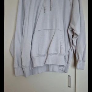 Beige hoodie från H&M - Säljer en mysig beige hoodie från H&M Basic. Den har en stor ficka fram och justerbar dragsko i huvan. Perfekt för kyliga dagar eller bara för att chilla hemma. Passar både till vardags och avslappnade tillfällen.