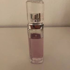 Hugo Boss parfym - Säljer en elegant ljusrosa parfymflaska med en stilren design. Flaskan har en fyrkantig form med en genomskinlig kork och silverdetaljer. Perfekt för den som älskar en fräsch och feminin doft. Passar både till vardags och fest!