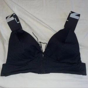 Svart sporttopp från Nebbia - Snygg svart sporttopp från Nebbia med breda axelband och logga. Toppen har en knytning framtill och en bekväm passform. Perfekt för träning eller en aktiv vardag.