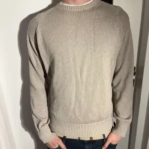 Säljer en stilren beige tröja från Reserved i storlek L. Tröjan är i mycket bra skick och har en klassisk design med ribbade muddar och rund hals. Perfekt för både höst och vår. Passar till både jeans och chinos för en avslappnad look. Modellen på bilden är 180 och tröjan passar som small.