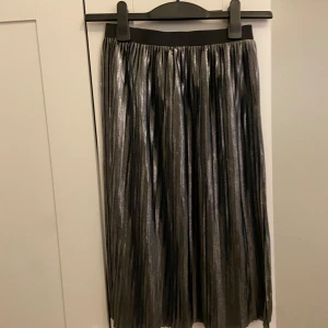 Silverfärgad kjol från Jacqueline de Yong - Snygg silverfärgad kjol från Jacqueline de Yong i storlek XS. Kjolen har en glittrig finish och är perfekt för festliga tillfällen. Den har en elastisk midja för en bekväm passform och är i ett lätt och flödande material. Den är även väldigt stretchig och perfekt till nyår💕