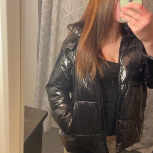 Svart glansig pufferjacka från Zara - Säljer en svart glansig pufferjacka i mycket bra skick. Den är ifrån zara från nått år sen så finns förmodligen inte kvar😊