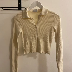 Beige ribbad croppad tröja - Säljer en superfin beige ribbad tröja med dragkedja och krage. Den är croppad och har långa ärmar, perfekt för en stilren look🧡