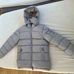 Grå pufferjacka från Moncler - Säljer en snygg grå pufferjacka från Moncler i helt nytt skick. Jackan är perfekt för vintern med sin varma och quiltade design. Den har en praktisk dragkedja och en justerbar huva. Storleken är herr S , och den är superbekväm och stilren. Perfekt för kalla dagar! ❄️
