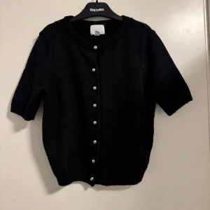 Svart kofta från H&M - Säljer en stilren svart kofta från H&M i storlek XS. Den har trekvartsärmar och knäpps med fina knappar framtill. Perfekt för både vardag och festliga tillfällen. 🖤