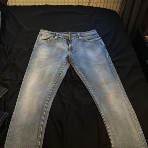 Blå jeans från Nudie Jeans - Säljer ett par snygga blå jeans från Nudie Jeans i bra skick. De har en klassisk femficksdesign och en bekväm passform. Perfekta för både vardag och fest! 🕺 nypris 1500kr och använt dem cirka 2 gånger